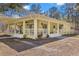 Yellow house with metal roof, large porch, and landscaped yard at 19256 Hidden Oaks Dr, Brooksville, FL 34604
