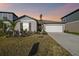 One-story house with gray siding, white garage door, and landscaped yard at dusk at 22103 Blazing Star Run, Land O Lakes, FL 34637