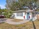 Front view of a charming white house with a blue door and well-manicured lawn at 3211 W Oakellar Ave, Tampa, FL 33611