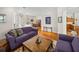 Open living room with hardwood floors, two purple sofas, and views into the kitchen and dining areas at 13315 Carnoustie Cir, Dade City, FL 33525