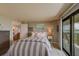 Bedroom with striped comforter and sliding glass door to balcony at 240 Sand Key Estates Dr # 213, Clearwater, FL 33767