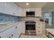 Updated kitchen featuring white cabinets, stainless steel appliances, and marble backsplash at 240 Sand Key Estates Dr # 213, Clearwater, FL 33767