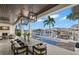 A covered outdoor space including a dining table and outdoor fireplace overlooking the pool and waterway at 2502 S Dundee St, Tampa, FL 33629