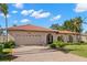 Tan house with a red tile roof, large garage, and a brick driveway at 350 6Th N Ave, Tierra Verde, FL 33715