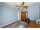 Bedroom with blue walls, wood floors, a ceiling fan, and a wood door with a mirror at 6254 Pershing Ne St, St Petersburg, FL 33702
