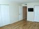 Bright bedroom with wood-look floors, double closets, and a view of a hallway at 946 Virginia St # 102, Dunedin, FL 34698