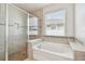 Bathroom with soaking tub and walk-in shower, tile surround, and window at 12332 Prairie Valley Ln, Riverview, FL 33579
