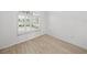 Bright bedroom featuring wood-look flooring and large window with shutters at 12632 Oak Hollow Ct, Dade City, FL 33525