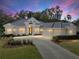Beautiful one-story home with a three-car garage, lush landscaping, and a circular driveway at 12632 Oak Hollow Ct, Dade City, FL 33525