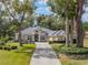 Tan house with a grey roof and lush landscaping at 12632 Oak Hollow Ct, Dade City, FL 33525