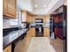 L-shaped kitchen with wood cabinets, granite countertops, and black appliances at 13600 Egret Blvd # 204K, Clearwater, FL 33762