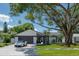Modern mid-century home with white brick exterior, dark gray garage door, and manicured landscaping at 14040 Cascade Ln, Tampa, FL 33618