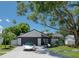 Mid-century home with white brick exterior, dark gray garage door, and lush landscaping at 14040 Cascade Ln, Tampa, FL 33618