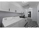 Bright laundry room with white cabinets, black countertops, and geometric tile floor at 14040 Cascade Ln, Tampa, FL 33618