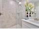 Detailed view of a walk-in shower with neutral tile, glass enclosure, and modern fixtures at 17014 Clear Cork Dr, Wimauma, FL 33598