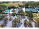 An aerial view of a community pool, tennis courts, and a clubhouse surrounded by trees at 335 Palmdale Dr, Oldsmar, FL 34677
