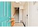Inviting entryway with teal door, wood shelf, and staircase at 3629 Gulf Blvd, St Pete Beach, FL 33706