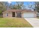 Beige house with brown roof, white garage door, and landscaped lawn at 5332 Nutcracker Cir, Land O Lakes, FL 34639