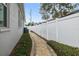 Side yard with a walkway, landscaping, and a white fence at 6224 S Main Ave, Tampa, FL 33611