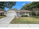 Brick ranch home with attached garage, and a well-manicured lawn at 10504 Tapestry Dr, Port Richey, FL 34668