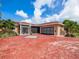 Tan house with red brick driveway, screened entryway, and two palm trees at 1818 Dolphin S Blvd, St Petersburg, FL 33707