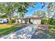 Cute ranch home with a paved driveway, mature landscaping, and a detached garage at 21 Belle Meade Cir, Largo, FL 33770