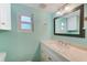 Bathroom with white vanity, a large mirror, and a window at 604 Pennsylvania Ave, Crystal Beach, FL 34681