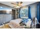 Bright bedroom featuring a ceiling fan, a large window with blue curtains, and closet storage at 612 12Th S Ave, St Petersburg, FL 33701