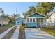 Charming blue bungalow featuring a quaint front porch and a long driveway to the garage at 612 12Th S Ave, St Petersburg, FL 33701