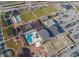 An aerial view of a community with multiple buildings, a pool, a tennis court, parking lots, and recreation areas at 1330 Misty Greens Dr, Sun City Center, FL 33573