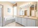 Bright bathroom featuring double sinks, a vanity and a tub at 1330 Misty Greens Dr, Sun City Center, FL 33573