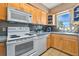 Galley kitchen with light wood cabinets, white appliances, and tile backsplash at 2533 Duncan Dr, Belleair Bluffs, FL 33770