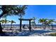 A gated beach access point leading to a gorgeous ocean view on a sunny day with a line of palm trees at 611 Destiny Dr # 410, Ruskin, FL 33570