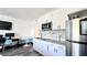 A modern kitchenette with stainless steel appliances and white cabinetry adjacent to the living area at 611 Destiny Dr # 410, Ruskin, FL 33570