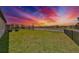 Expansive backyard with a black metal fence, lush lawn, and serene waterfront view beneath a vibrant sunset at 9608 Ivory Dr, Ruskin, FL 33573