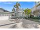 Stunning waterfront home with a light teal exterior, palm trees, and a two-car garage at 17077 Dolphin Dr, North Redington Beach, FL 33708