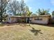 Tan house with blue door, landscaped yard and driveway at 400 Country Club Dr, Oldsmar, FL 34677