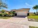 Tan house with tile roof, two-car garage, and landscaping at 4935 Marble Springs Cir, Wimauma, FL 33598