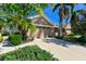 Tan house with two-car garage, lush landscaping, and a paved driveway at 7402 Hamilton Rd, Bradenton, FL 34209