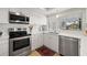 Modern white kitchen with stainless steel appliances and a quartz countertop at 1 Gallinule Pl, Belleair, FL 33756