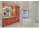 Bright bathroom featuring a soaking tub with marble surround and double window bringing in natural light at 1097 Eden Isle Ne Dr, St Petersburg, FL 33704