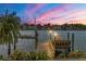 Sunset view of a private dock along the water, enhanced by flowers and colorful sky at 1097 Eden Isle Ne Dr, St Petersburg, FL 33704