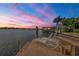 A private wooden dock with chairs and a bench overlooks the calm water at sunset at 1097 Eden Isle Ne Dr, St Petersburg, FL 33704