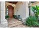 Close-up of front entrance with a wood door, decorative archway, and manicured landscaping at 1097 Eden Isle Ne Dr, St Petersburg, FL 33704