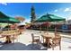 Outdoor patio area with wooden tables, chairs, and umbrellas, adjacent to landscaped garden at 1366 Stafford Ln # 1420, Sarasota, FL 34232