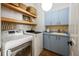 Functional laundry room with modern washer and dryer, blue cabinets, and stylish shelving for storage at 1893 Riveredge Dr, Tarpon Springs, FL 34689