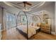 Cozy main bedroom featuring a tray ceiling, hardwood floors, canopy bed, and bright windows at 1893 Riveredge Dr, Tarpon Springs, FL 34689