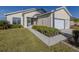 Tan house with white trim, screened porch, and attached garage. Landscaped lawn and walkway at 24156 Buckingham Way, Punta Gorda, FL 33980