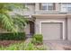 Townhome entrance with a two-car garage and lush landscaping at 26914 Juniper Bay Dr, Wesley Chapel, FL 33544