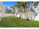 Well-maintained backyard with lush green grass and a white privacy fence lined with mature palm trees at 3107 W Palmira Ave, Tampa, FL 33629